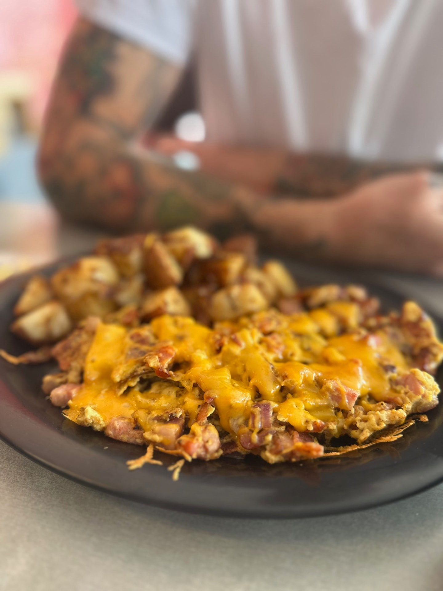 A savory breakfast skillet with potatoes and melted cheddar at Rooster Cafe